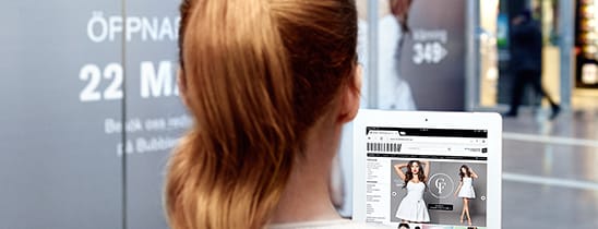 En person med långt hår tittar på webbsida med vita klänningar på iPad