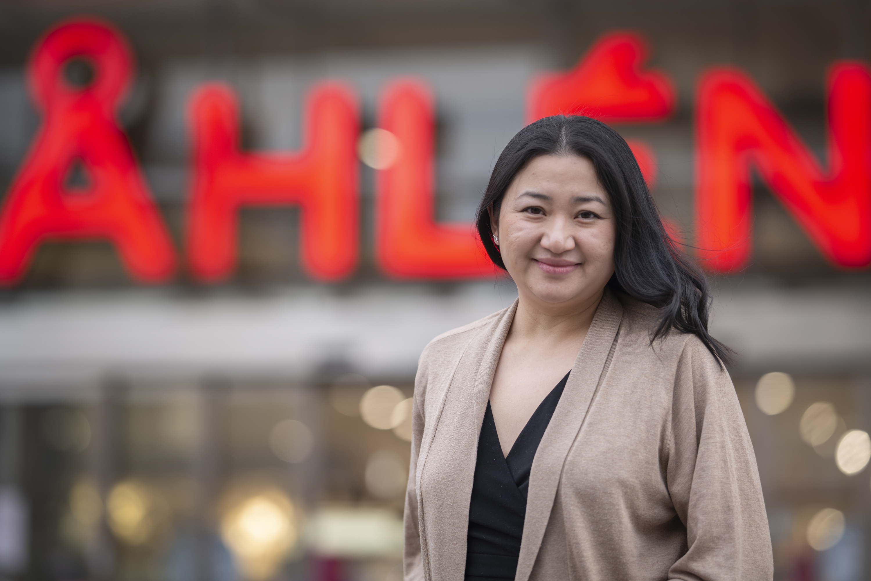 Jenny Zeng, e-handelschef på Åhléns, står framför en upplyst Åhléns-skylt.
