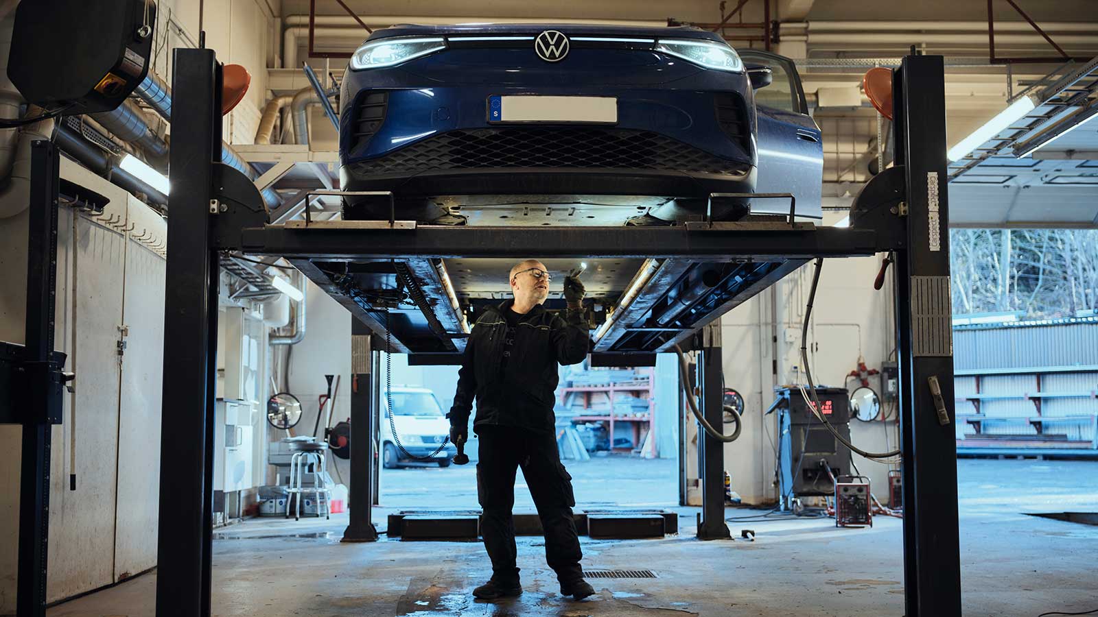 Man på verkstad som meckar under en bil.