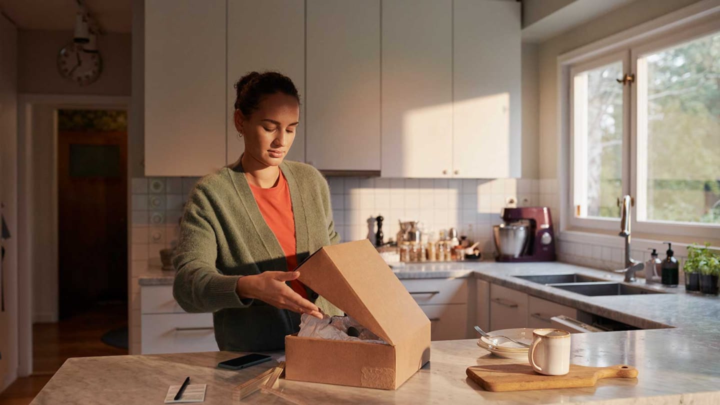 Kvinna som öppnar ett paket i sitt kök.